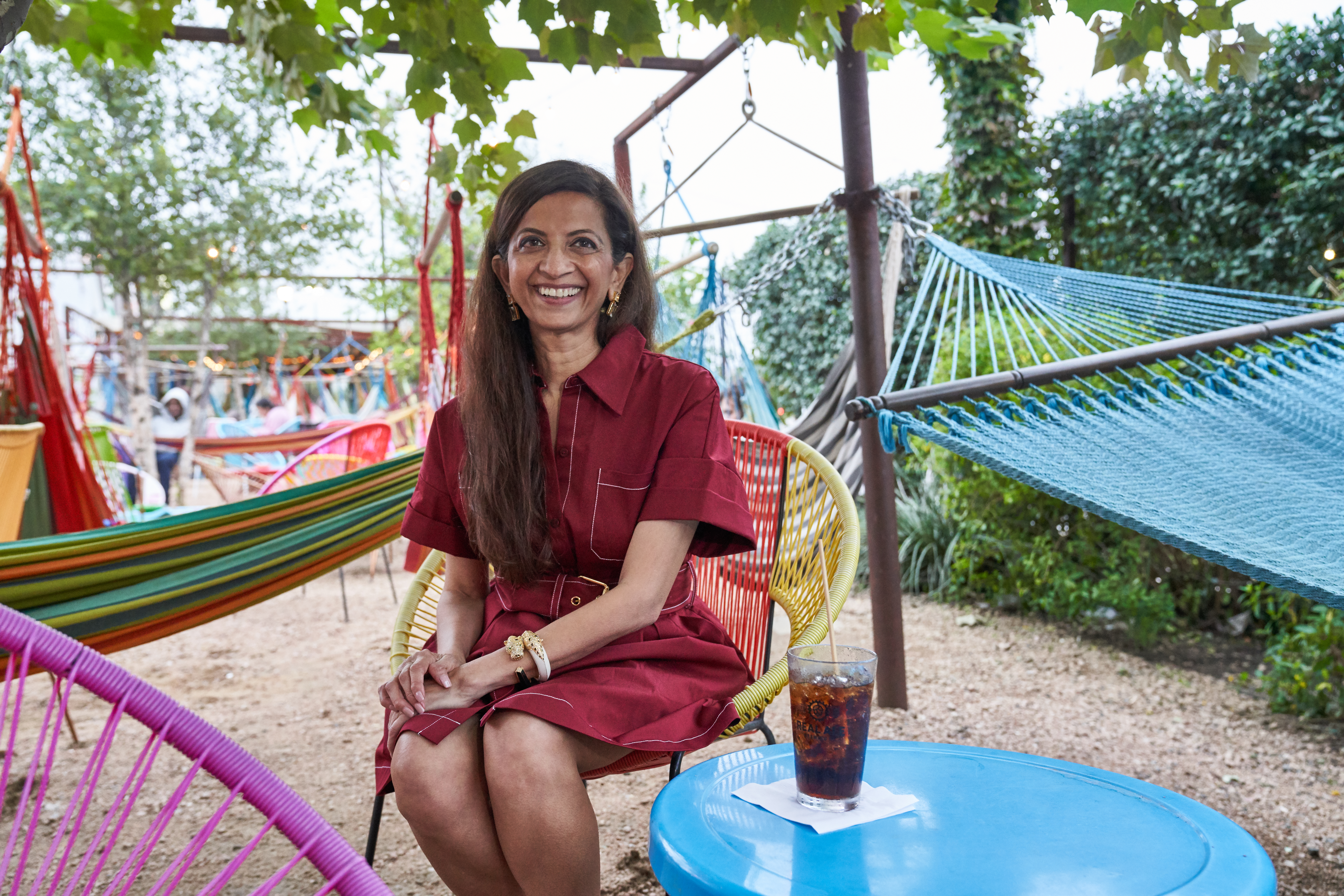 Woman sitting in hammock outside smiling at camera