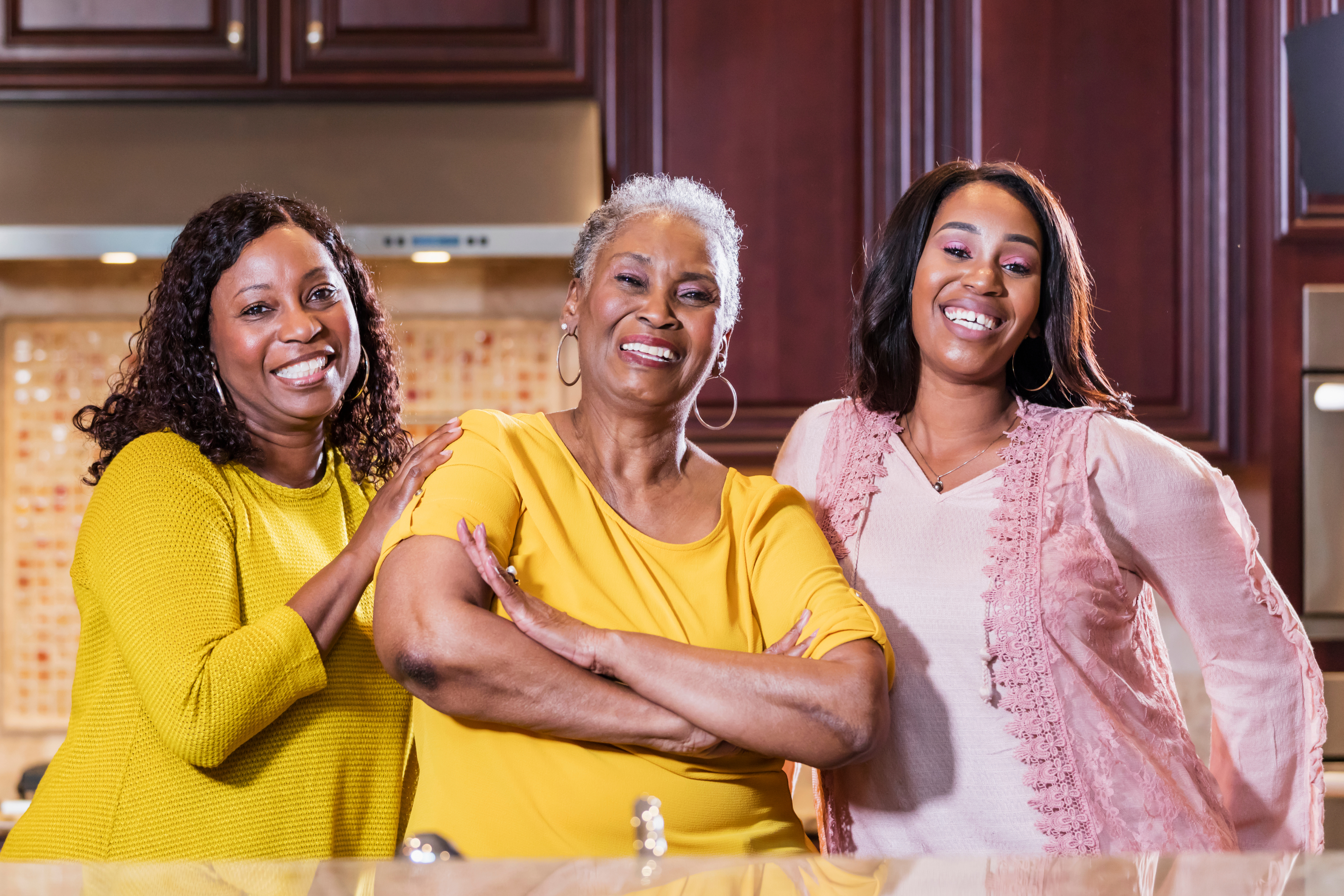 Mother and two daughters standing in kitchen, smiling, looking at camera